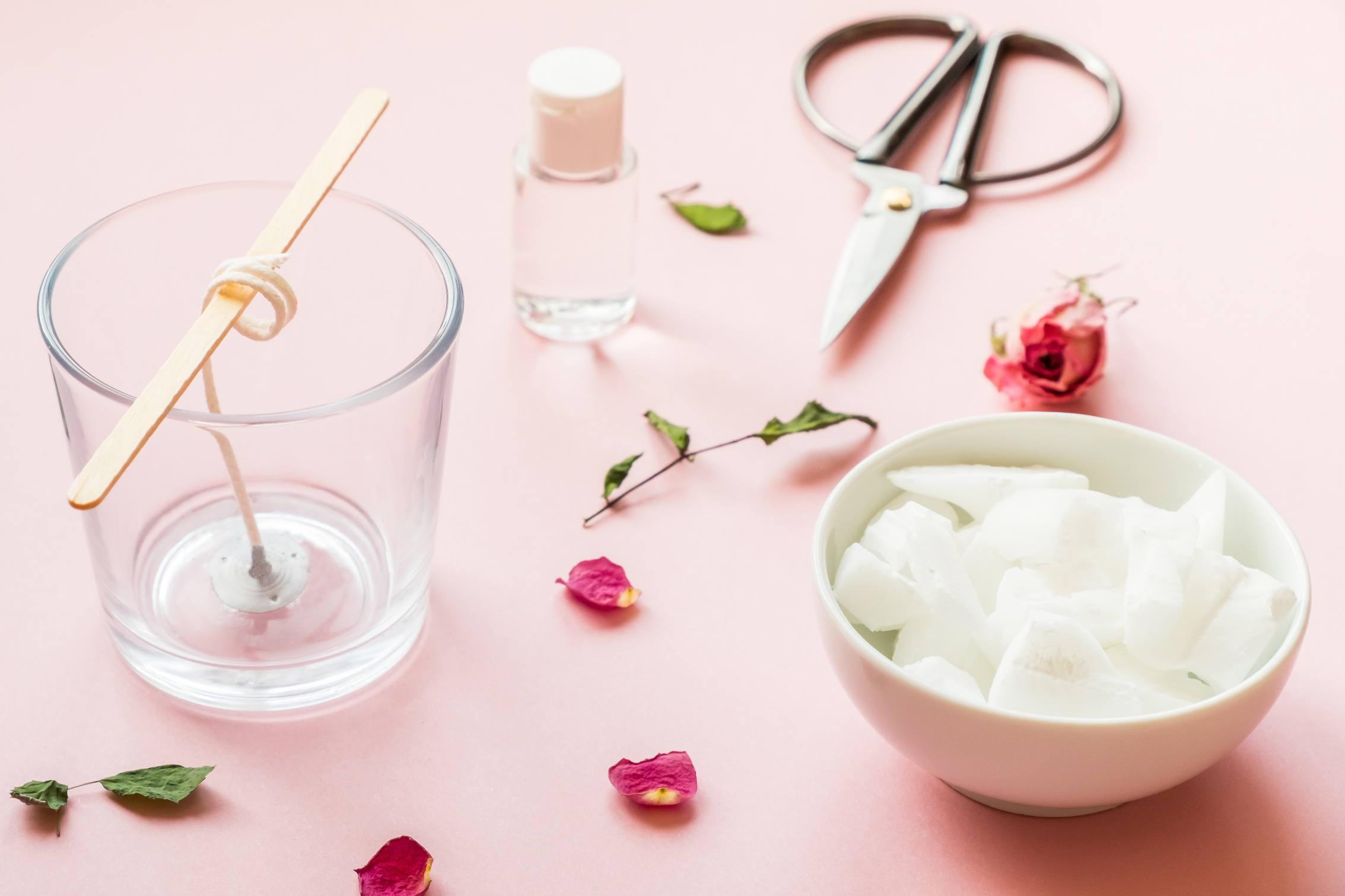 DIY concept. Wax, wick, dry roses - ingredients for making handmade candles on a pink background.
